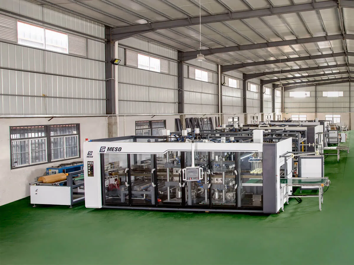 A large MESO-branded thermoforming machine inside a clean and spacious factory.