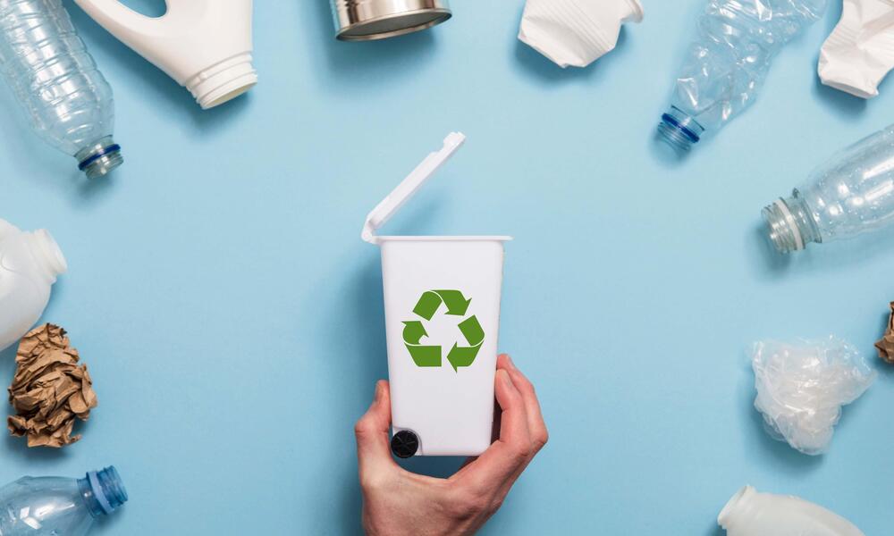 Recycling concept with various plastic waste and a recycling bin.