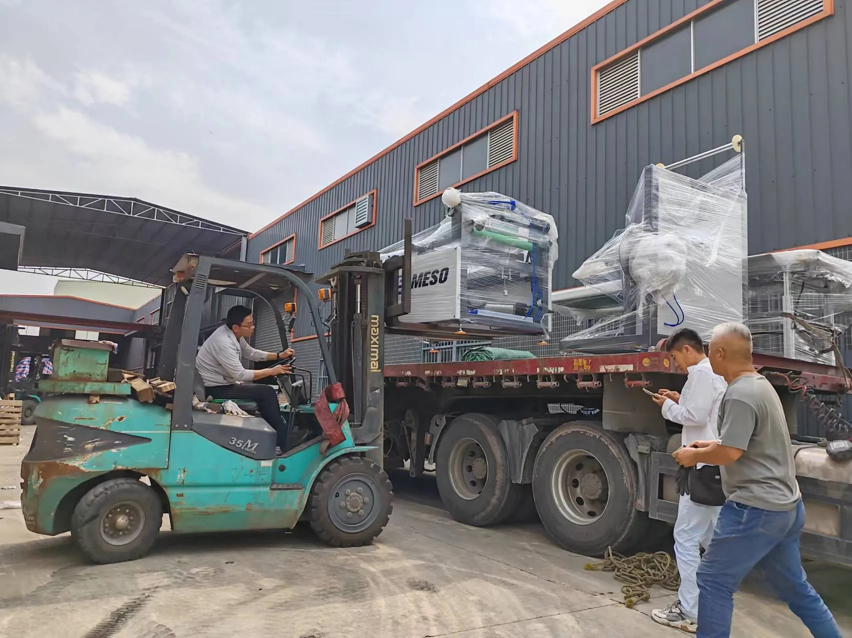 Forklift loading a thermoforming machine onto a truck