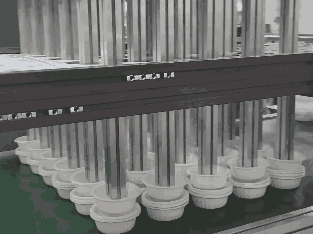 An automated system stacking plastic cup lids using a series of vertical metal rods, neatly organizing them on a conveyor belt.