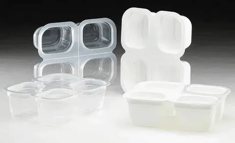 Two multi-compartment thermoformed plastic containers, one clear and one opaque, used for packaging food items.