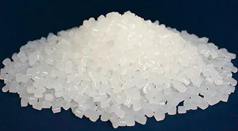 A pile of clear, high-purity PET resin pellets used in the thermoforming process.