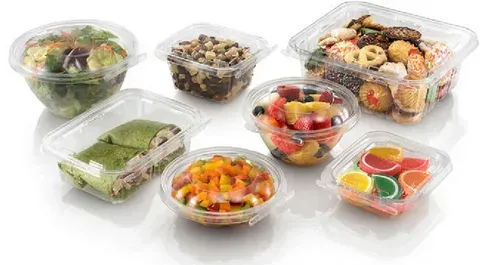 Assorted food items in clear PET clamshell containers, including salads, wraps, fruit, and desserts.